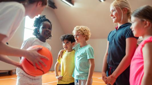 coach teaching basketball to children